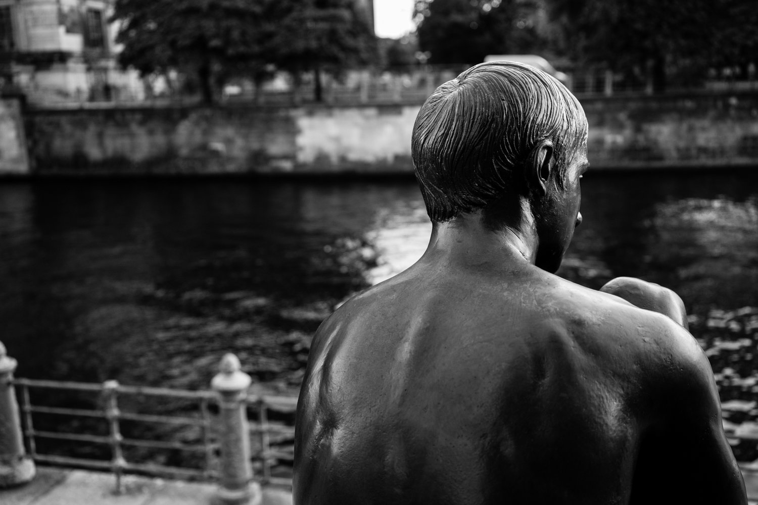 spree river berlin - statue of man by waterfront